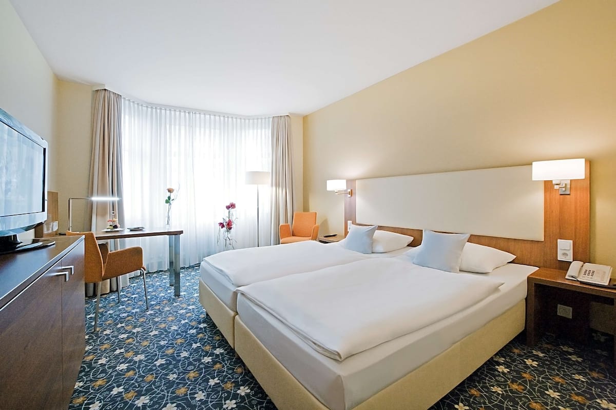 Une chambre d  ’hôtel avec deux lits, un bureau, une télévision et un téléphone.