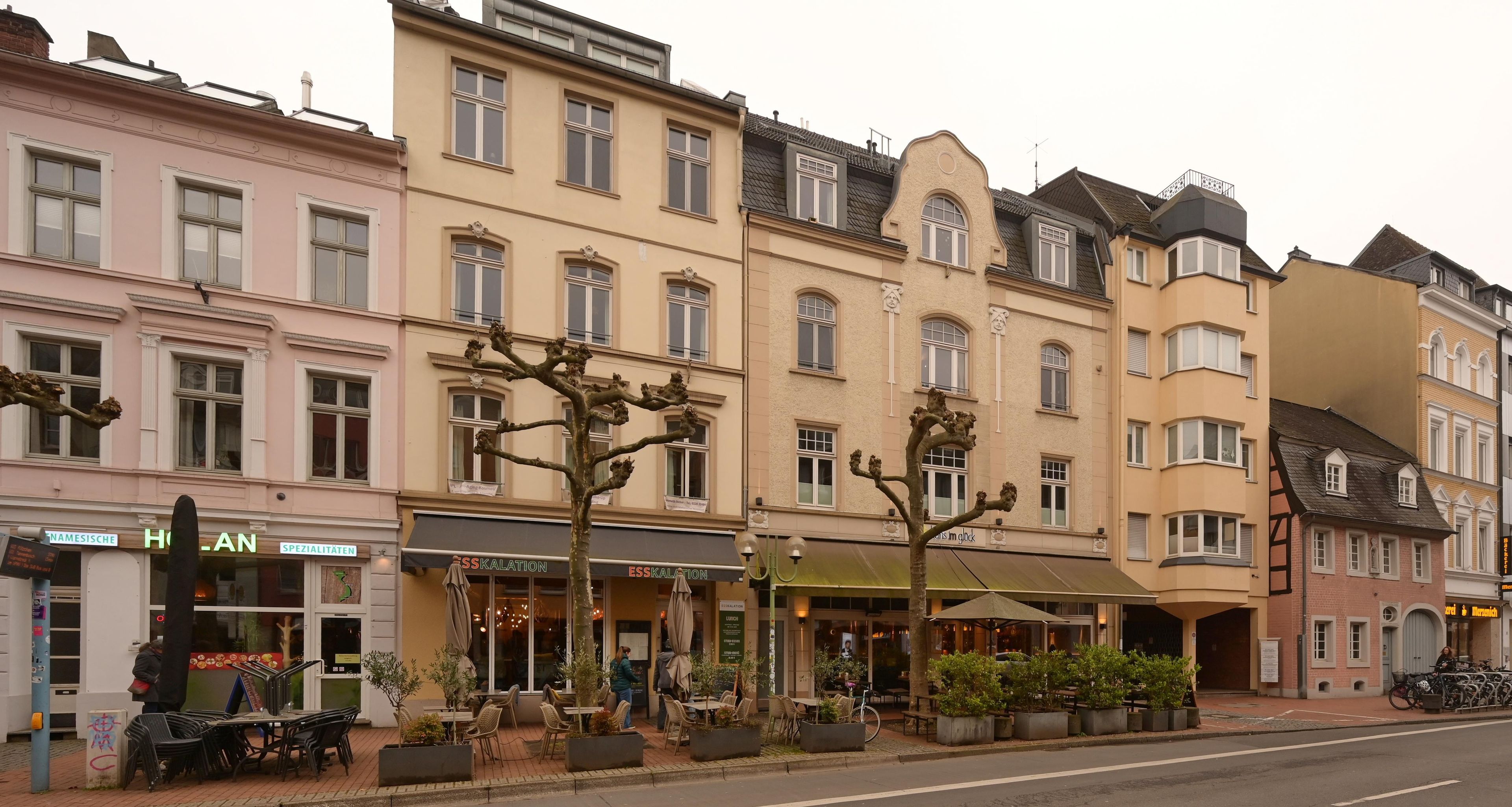 A row of multi-story buildings with ground-floor commercial establishments, including a restaurant and a café.