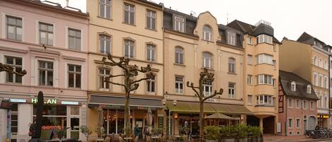 A row of multi-story buildings with ground-floor commercial establishments, including a restaurant and a café.