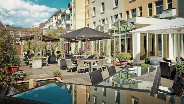A rooftop pool area with outdoor seating and a view of surrounding buildings.