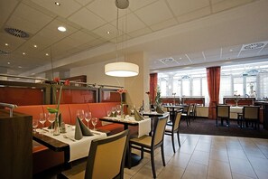 A restaurant with booths and tables, some with white tablecloths and wine glasses. - Best Western Hotel President (Bonn)