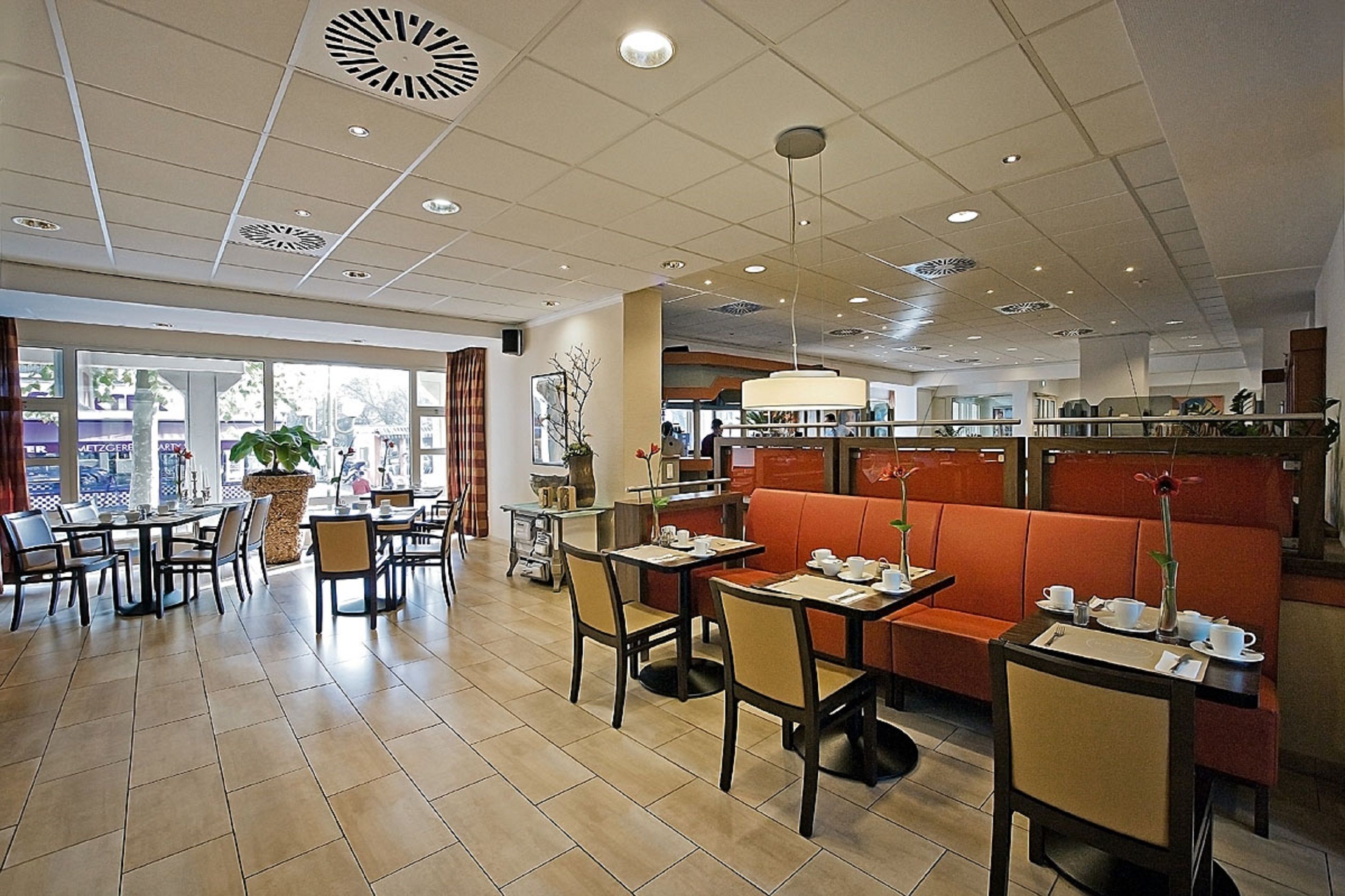 A restaurant with booths and tables, a large window, and a ceiling with recessed lighting.