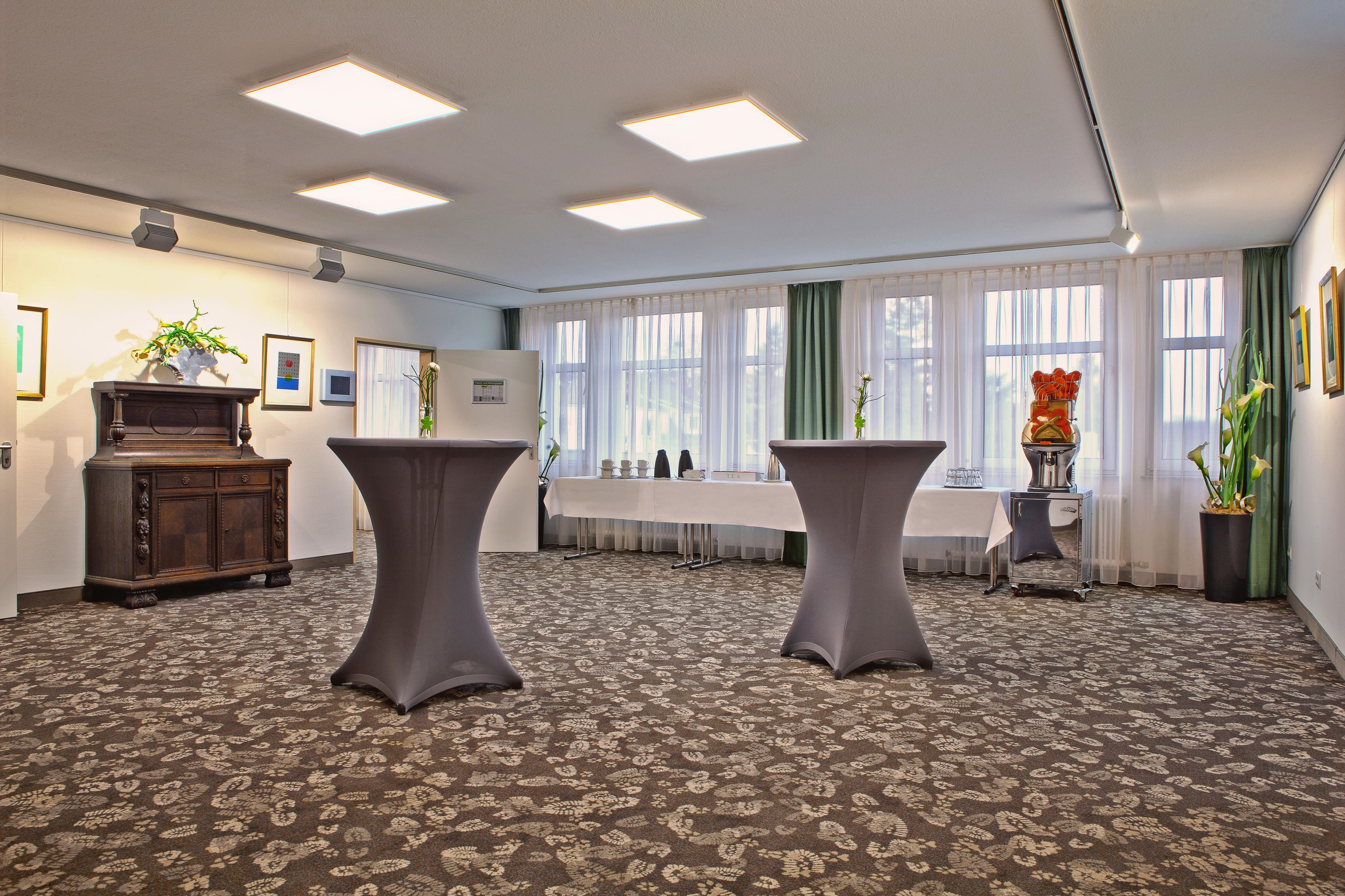 Ein Konferenzraum mit einem großen Tisch, zwei Hockern, einem Schrank und einem Blumentopf.