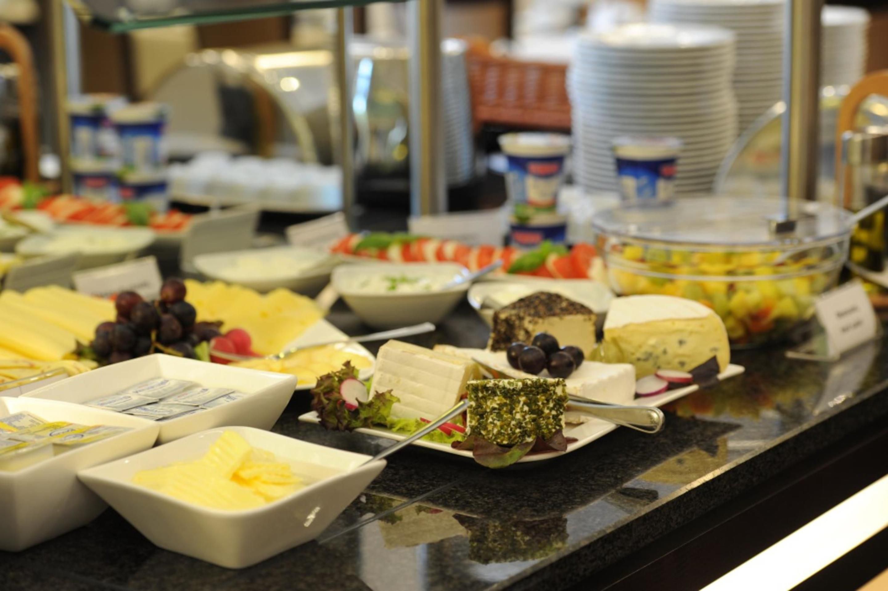 A buffet with various cheeses, fruits, and salads.