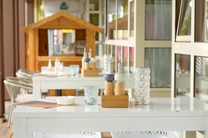 A hotel room with a white table set with various items including a candle, a glass, and a wooden block.