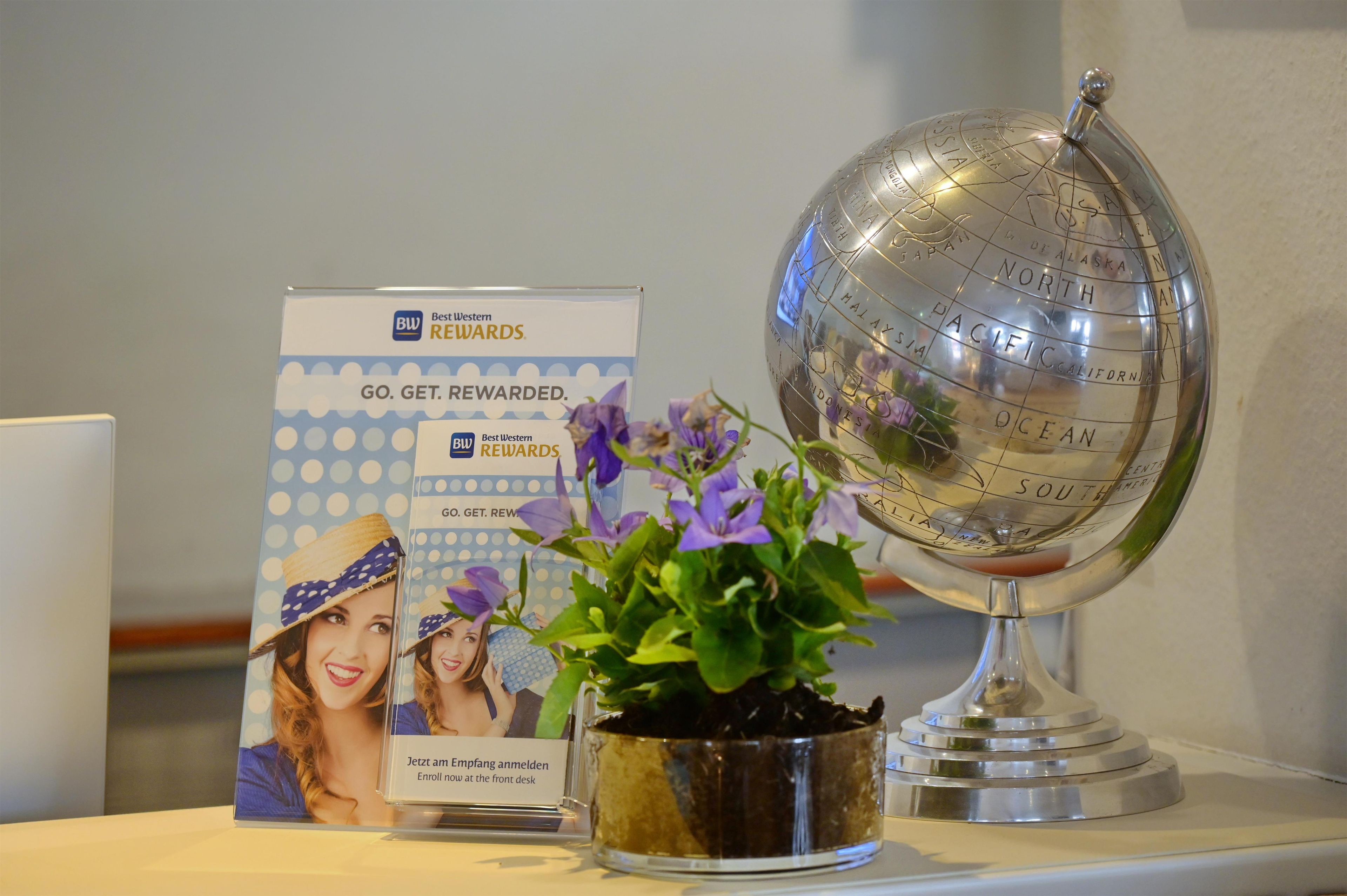 A promotional display with a globe, a sign for Best Western Rewards, and a potted plant.