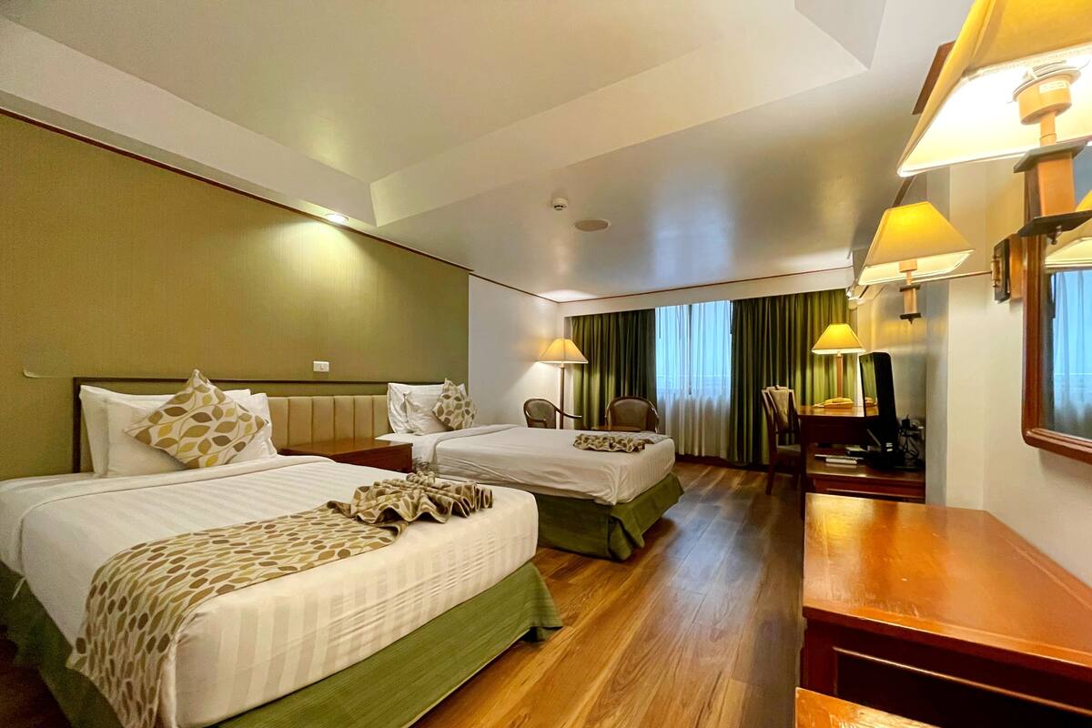 Een hotelkamer met twee bedden, een bureau en een stoel.