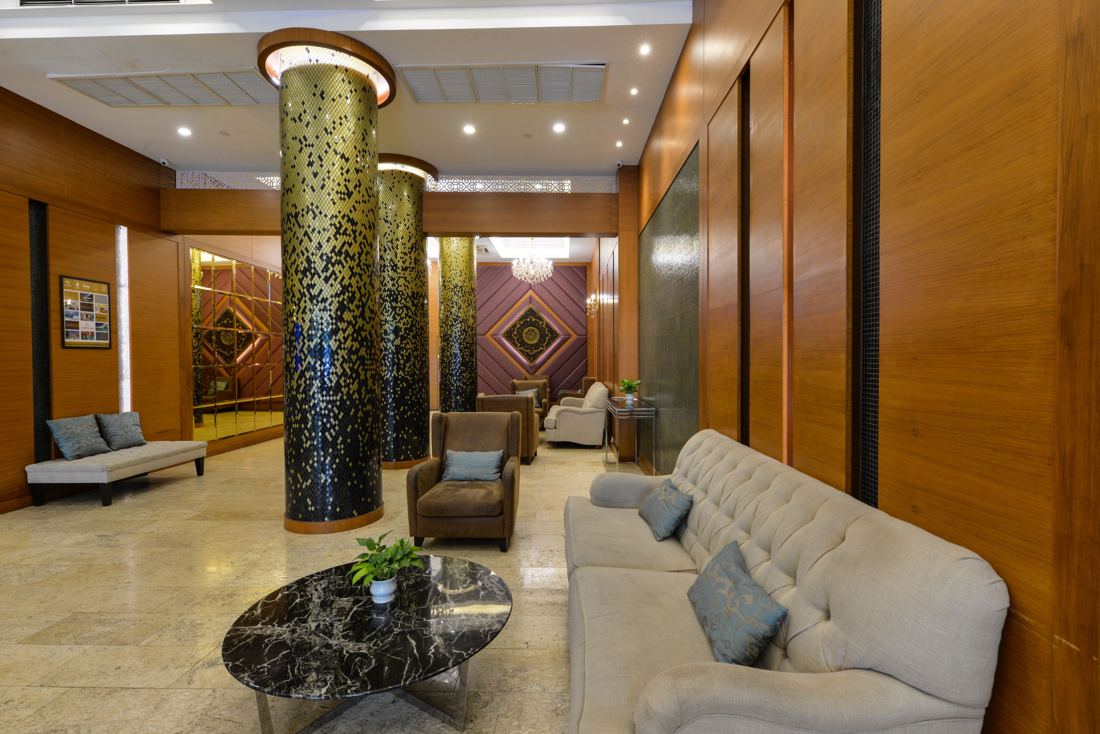 Eine Lobby mit einer Couch, Sesseln, einem Couchtisch und dekorativen Säulen.