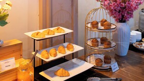 A buffet table with croissants, muffins, and honey.