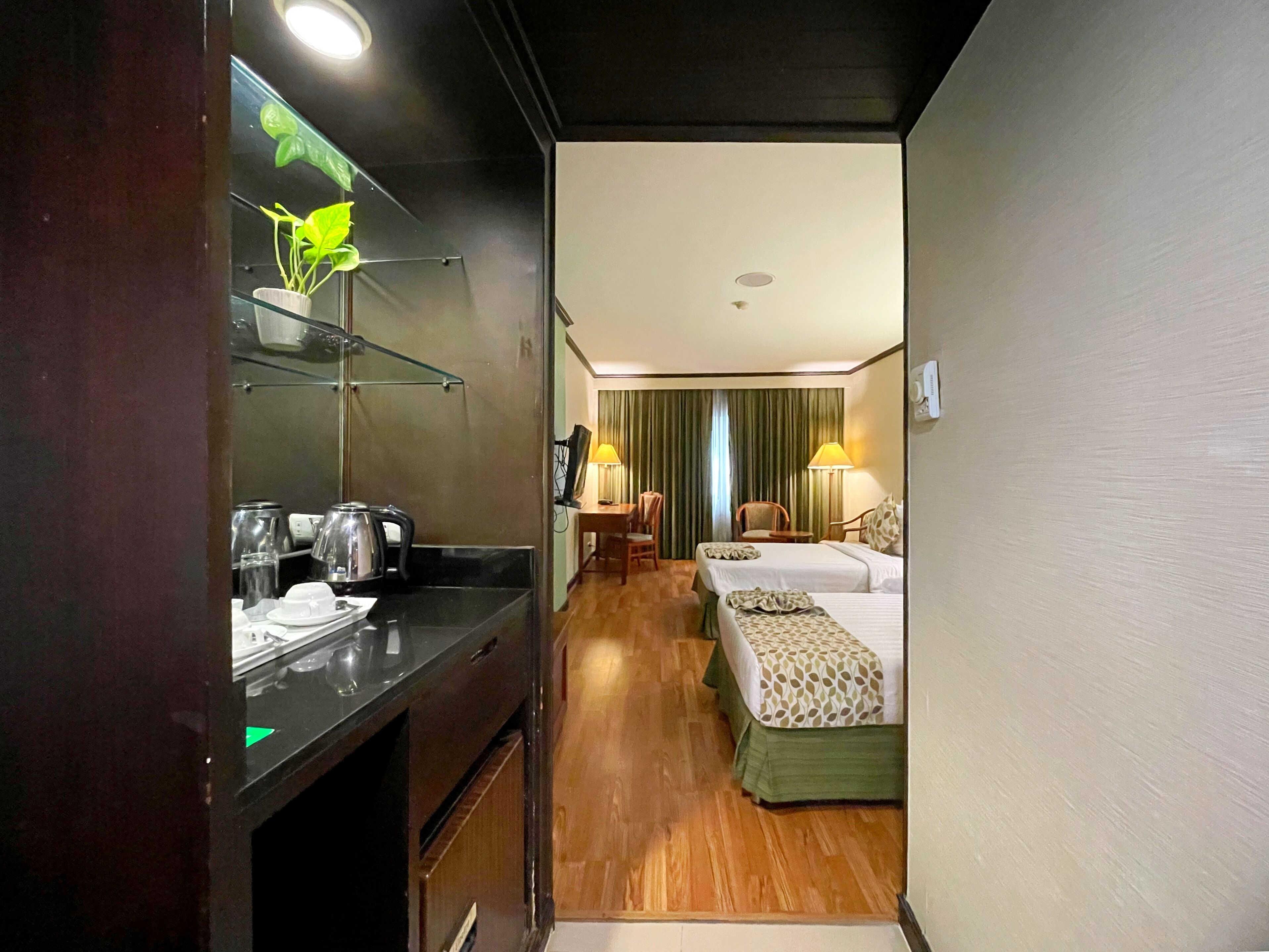 Ein Hotelzimmer mit Küchenzeile, zwei Betten, einem Schreibtisch und einem Stuhl.