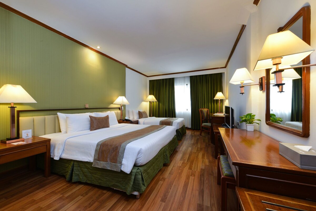 Een hotelkamer met twee bedden, een bureau, een stoel, een televisie en een spiegel.
