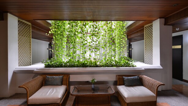A seating area with wicker furniture and a glass-top table, surrounded by a vertical garden.