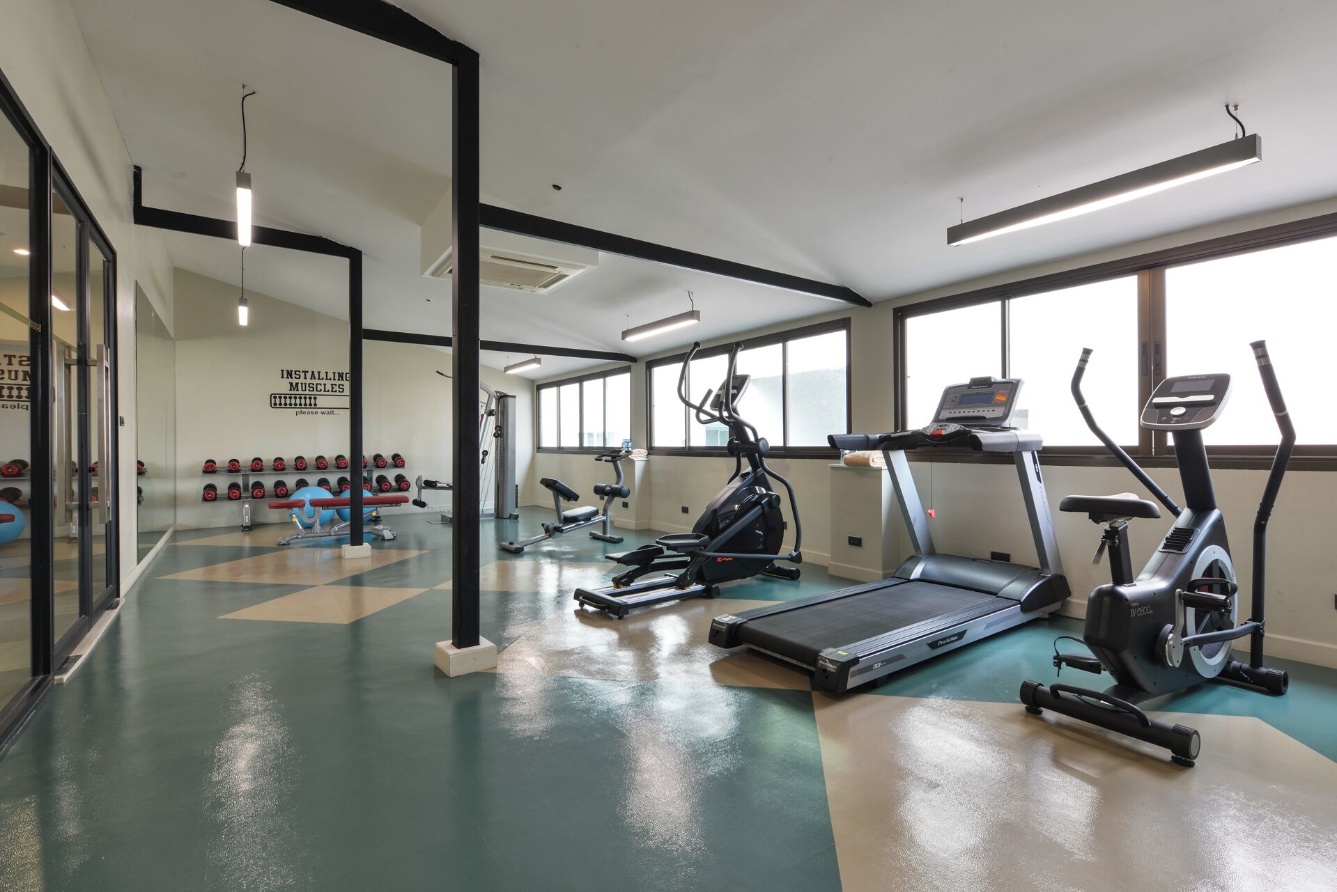 A gym with treadmills, elliptical machines, and free weights.