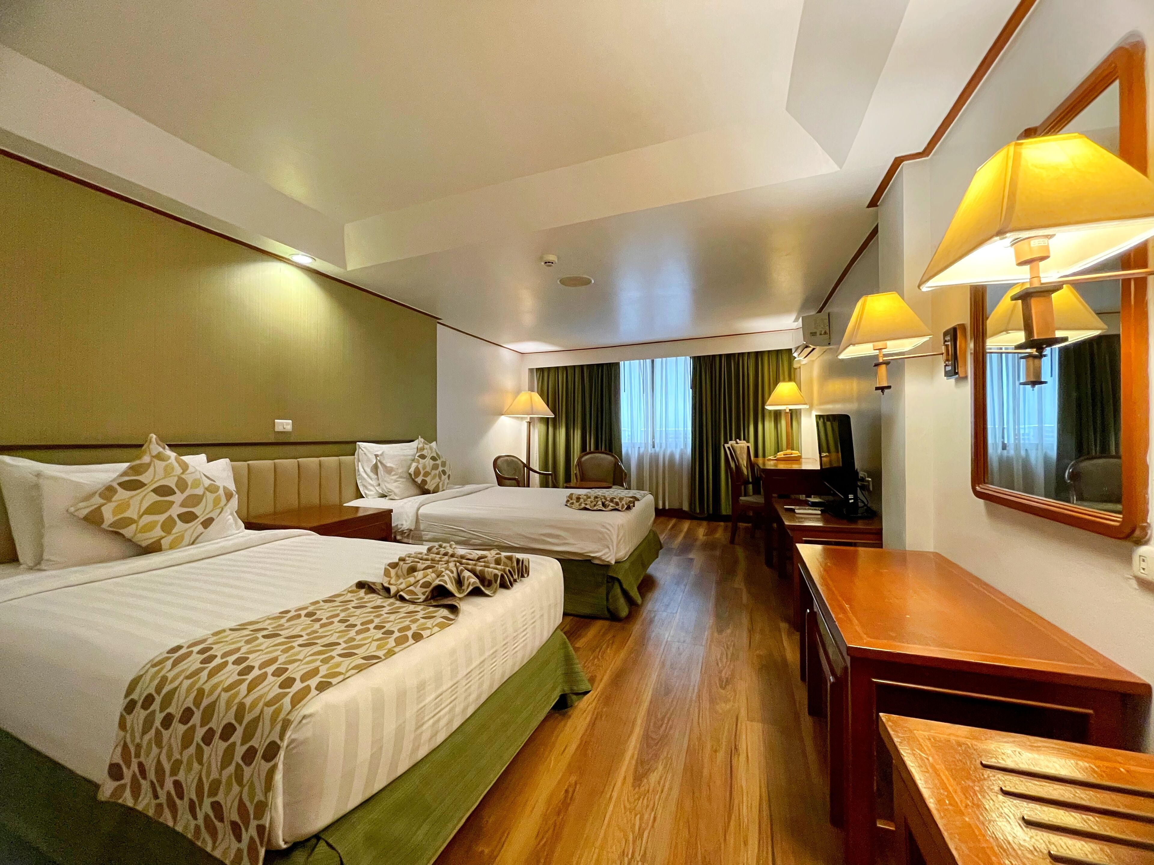 Une chambre d’hôtel avec deux lits, un bureau, une chaise et un téléviseur.