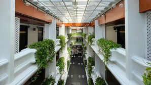 A modern atrium with a glass ceiling, white columns, and green plants.