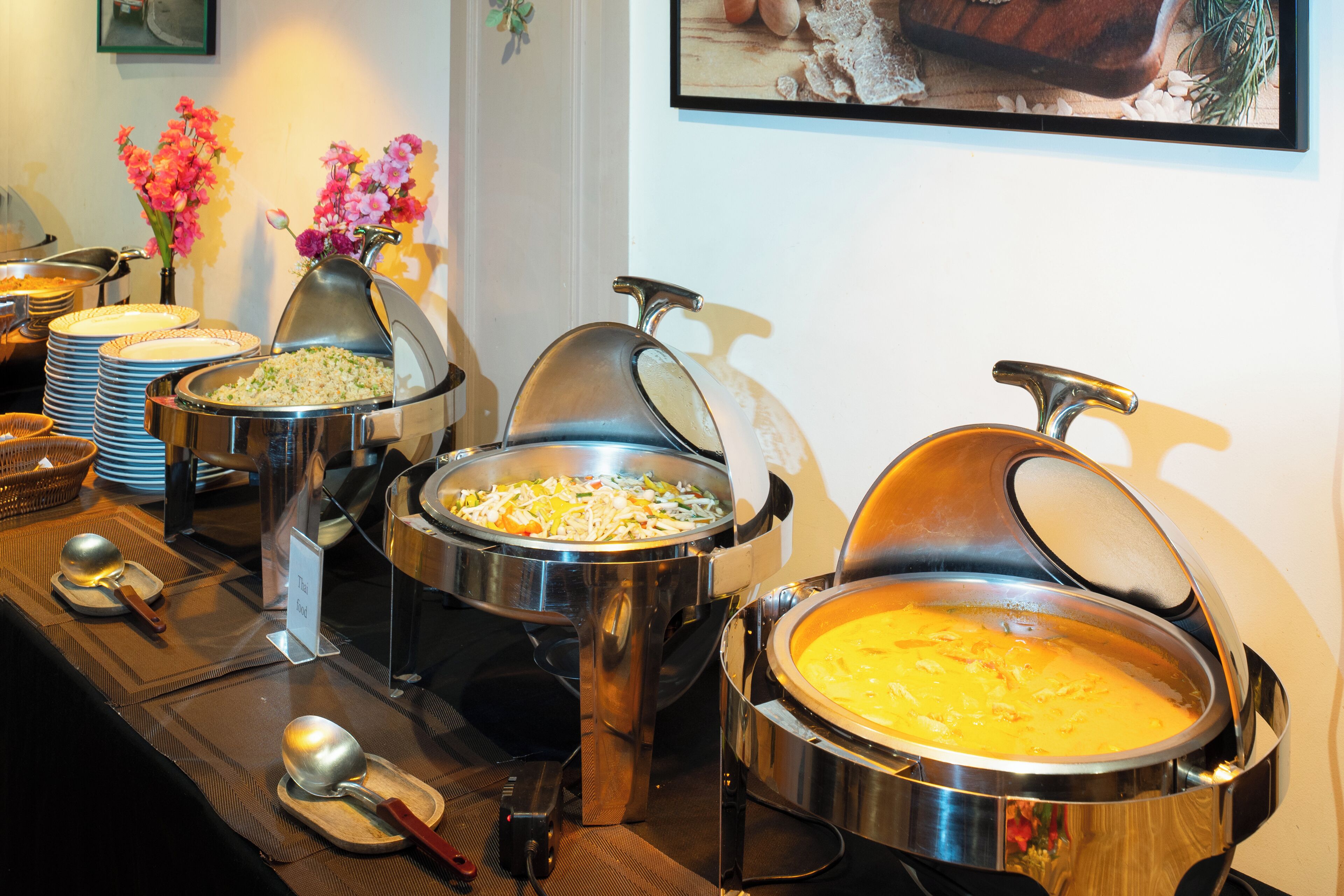 A buffet setup with various food containers and serving utensils.
