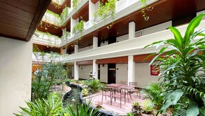 A multi-level atrium with a central water feature, surrounded by lush greenery and seating areas.