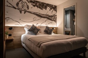 A bedroom with a large bed, two decorative pillows, a nightstand with a plant, and a wall mural. - Nouveau Paris Park Hotel (Paris)