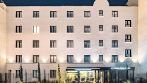 Un hotel de varios pisos con fachada simétrica, ventanas distribuidas uniformemente y una entrada central con dosel.