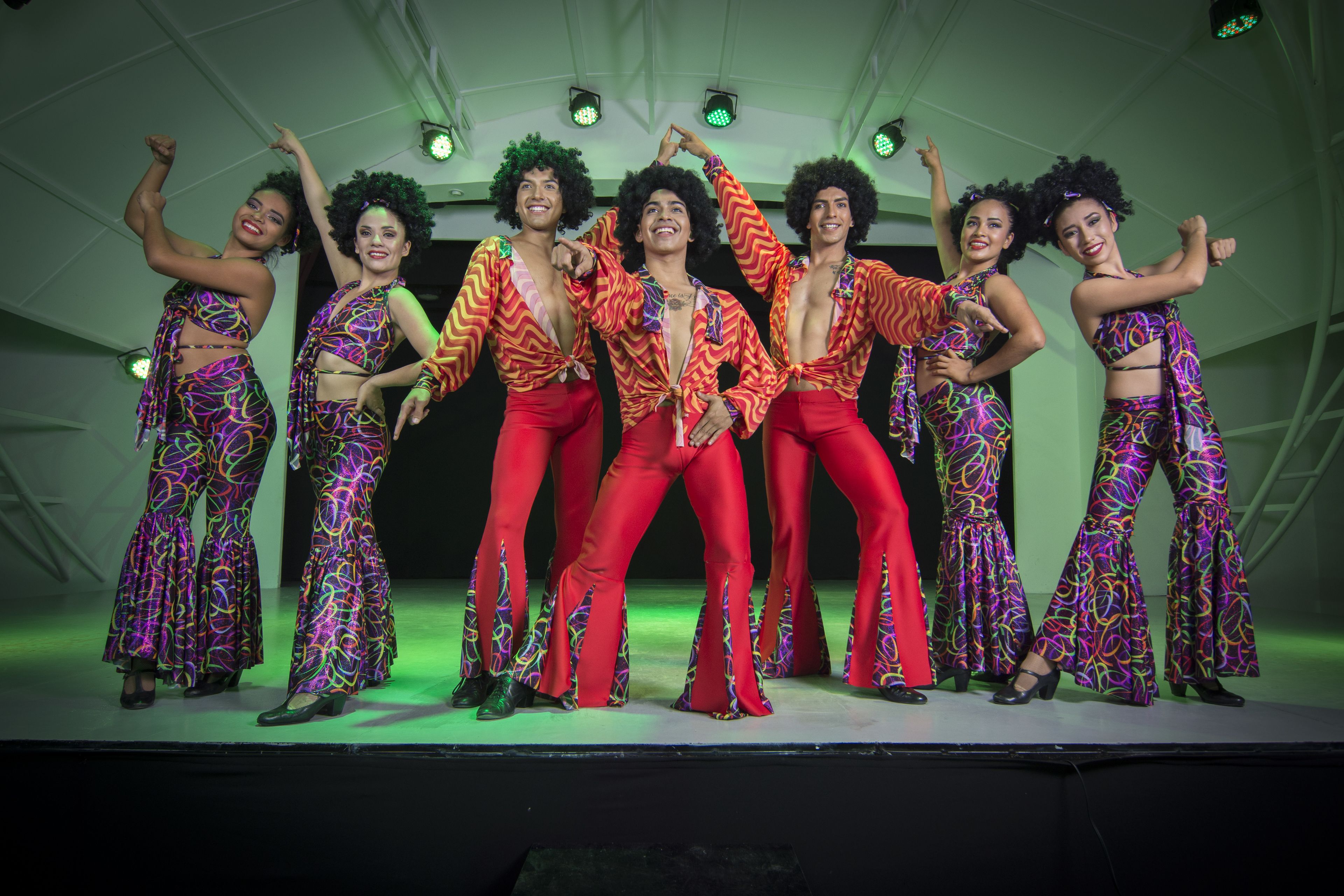 A group of people on a stage with a green-lit background.