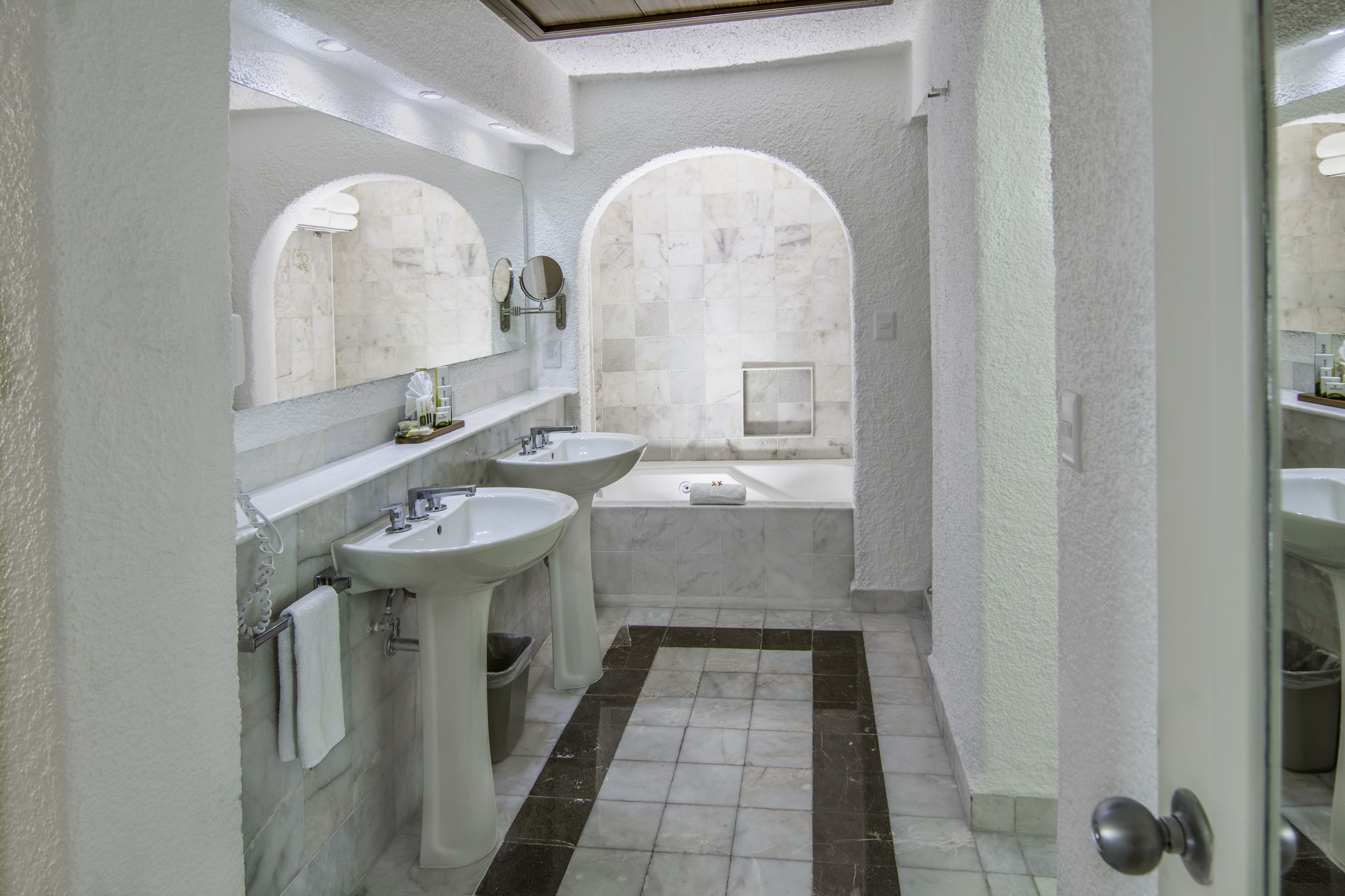 Un baño con dos lavamanos, una bañera y una ducha.
