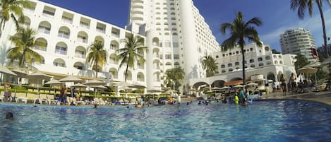 Una piscina al aire libre, sombrillas, sillones reclinables de piscina