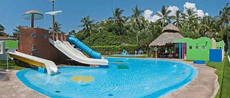 Parque acuático con una piscina grande, toboganes y una cabaña de techo de paja.