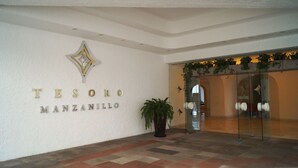 Entrada de un hotel con un cartel que dice "TESORO MANZANILLO".