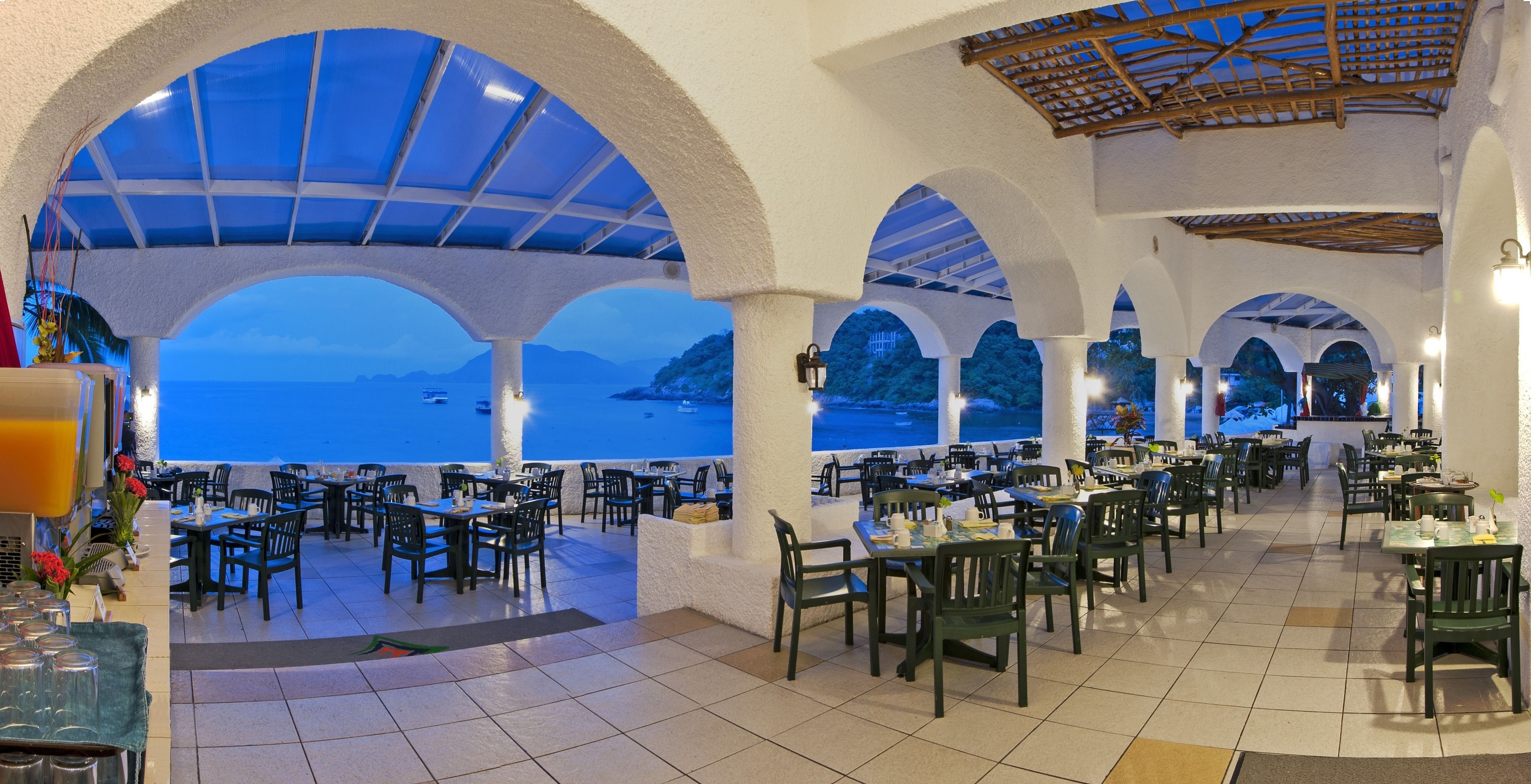 Un restaurant doté d’une terrasse offrant une vue sur la mer, avec des arches blanches et un sol carrelé.