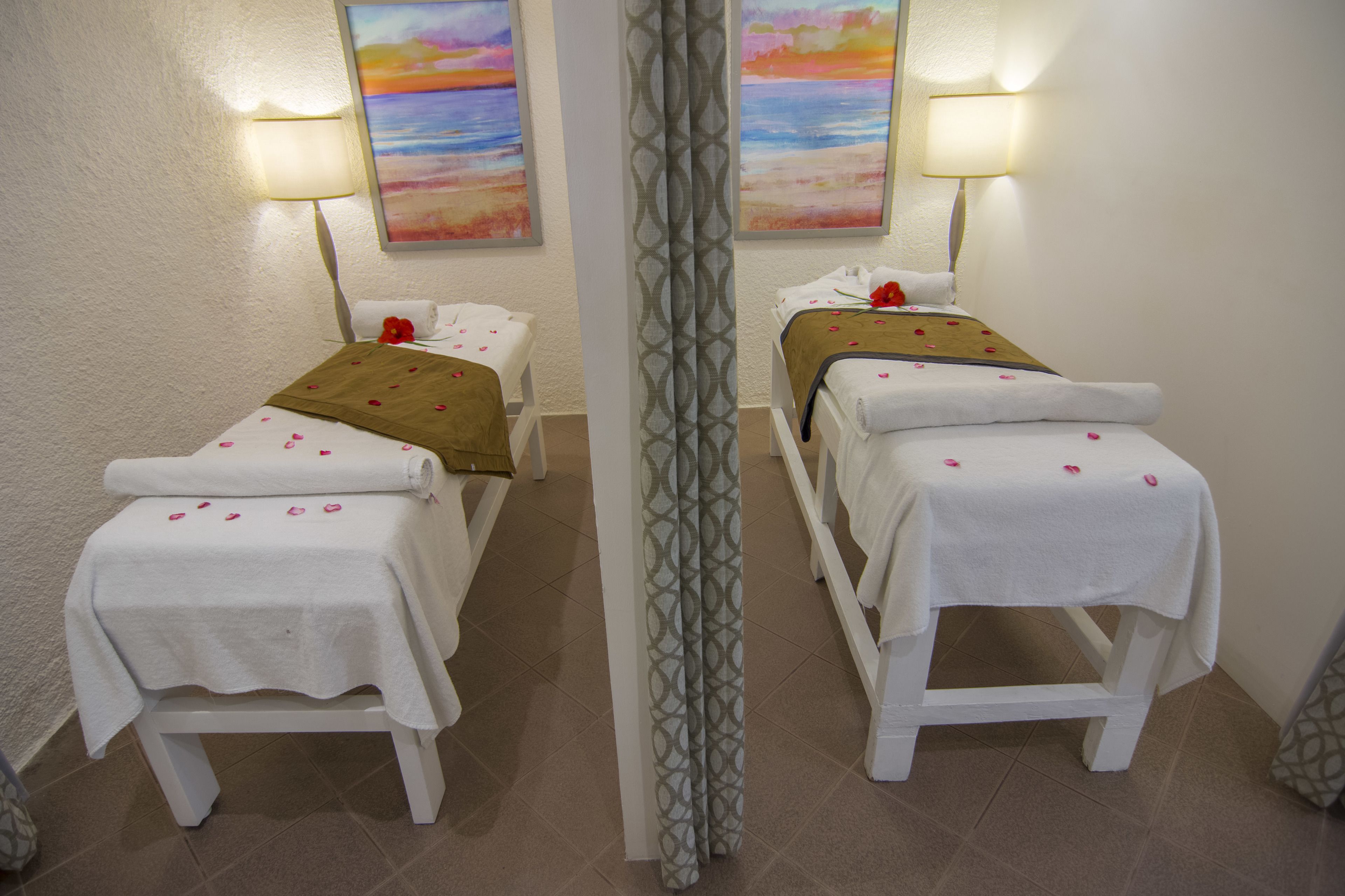 A room with two beds, each with a white bedspread and a brown blanket, and a mirror between them.