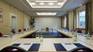 Une salle de conférence équipée de longues tables, de chaises et de verres.