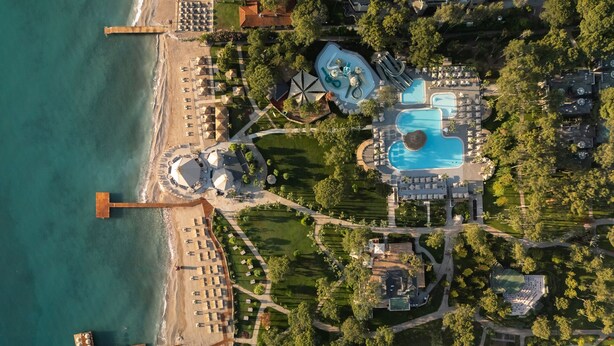 An aerial view of a resort with a beach, swimming pools, and tennis courts. - Balmy Foresta - All inclusive (Kemer)