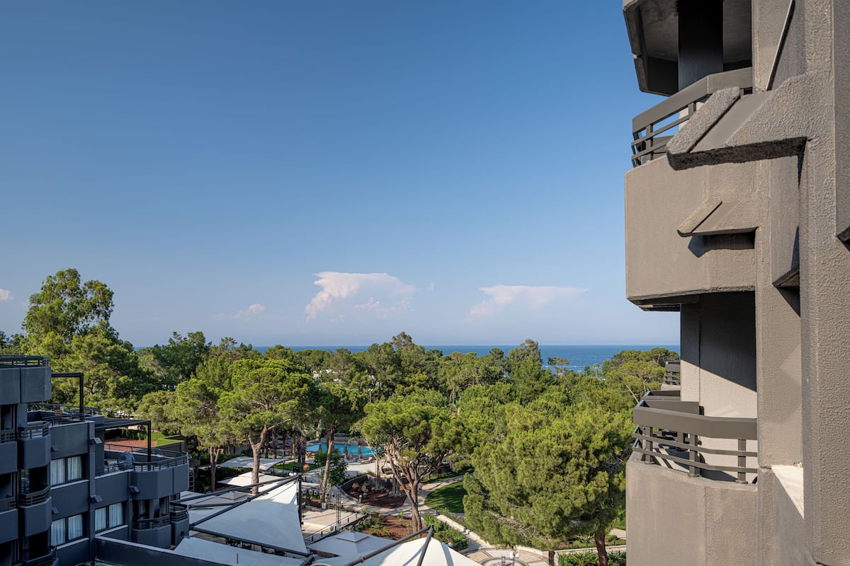 Um edifício alto com vista para uma piscina e árvores.