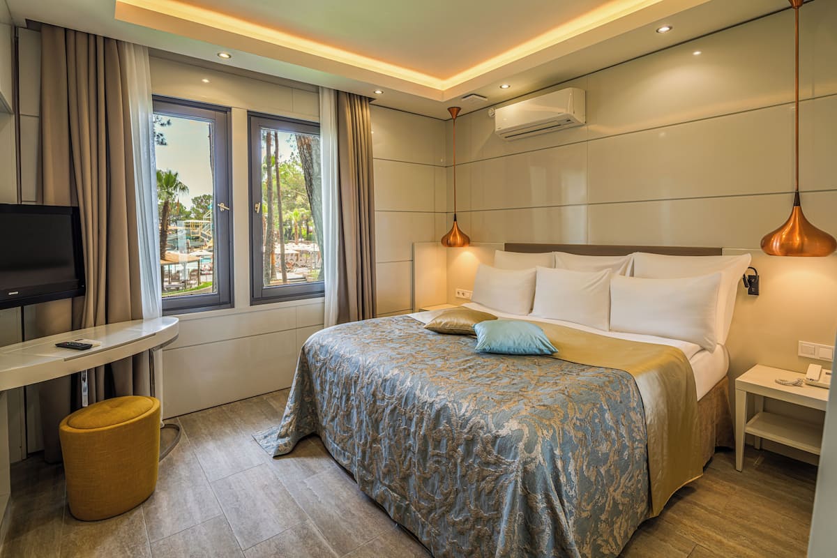 Quarto de hotel moderno com cama, escrivaninha e televisão.