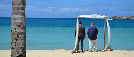 Decoración de boda en la playa, con un toldo y adornos florales.
