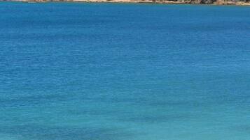 Un jet ski rouge sur une eau bleue et calme, avec un paysage côtier en arrière-plan.
