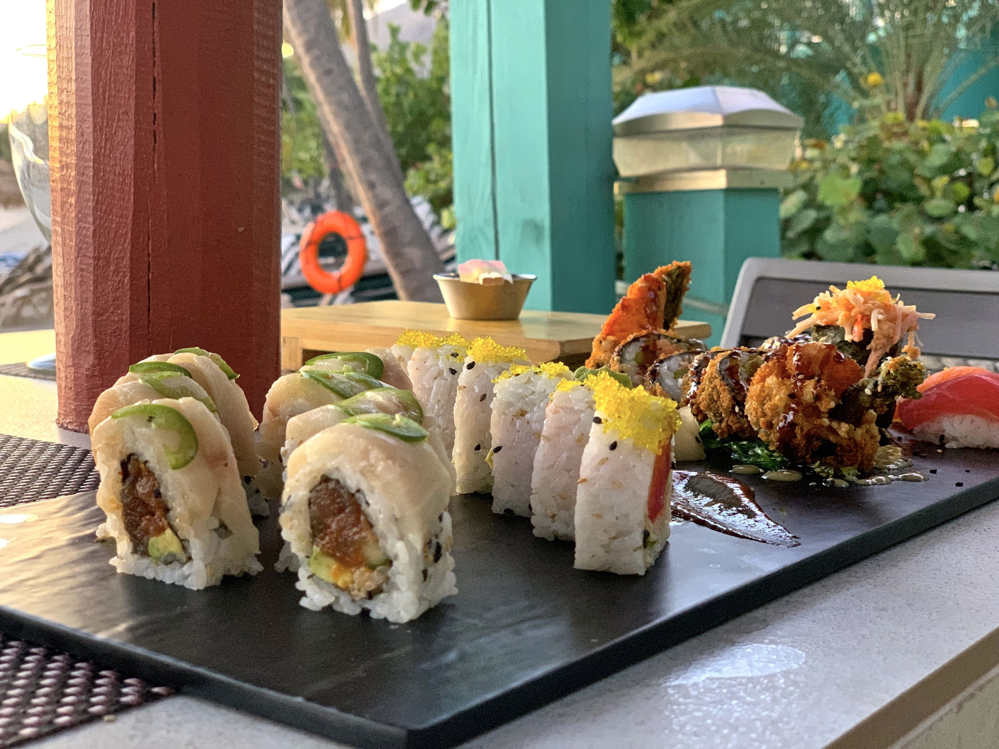 Una bandeja de sushi con diferentes tipos de sushi sobre un plato negro.