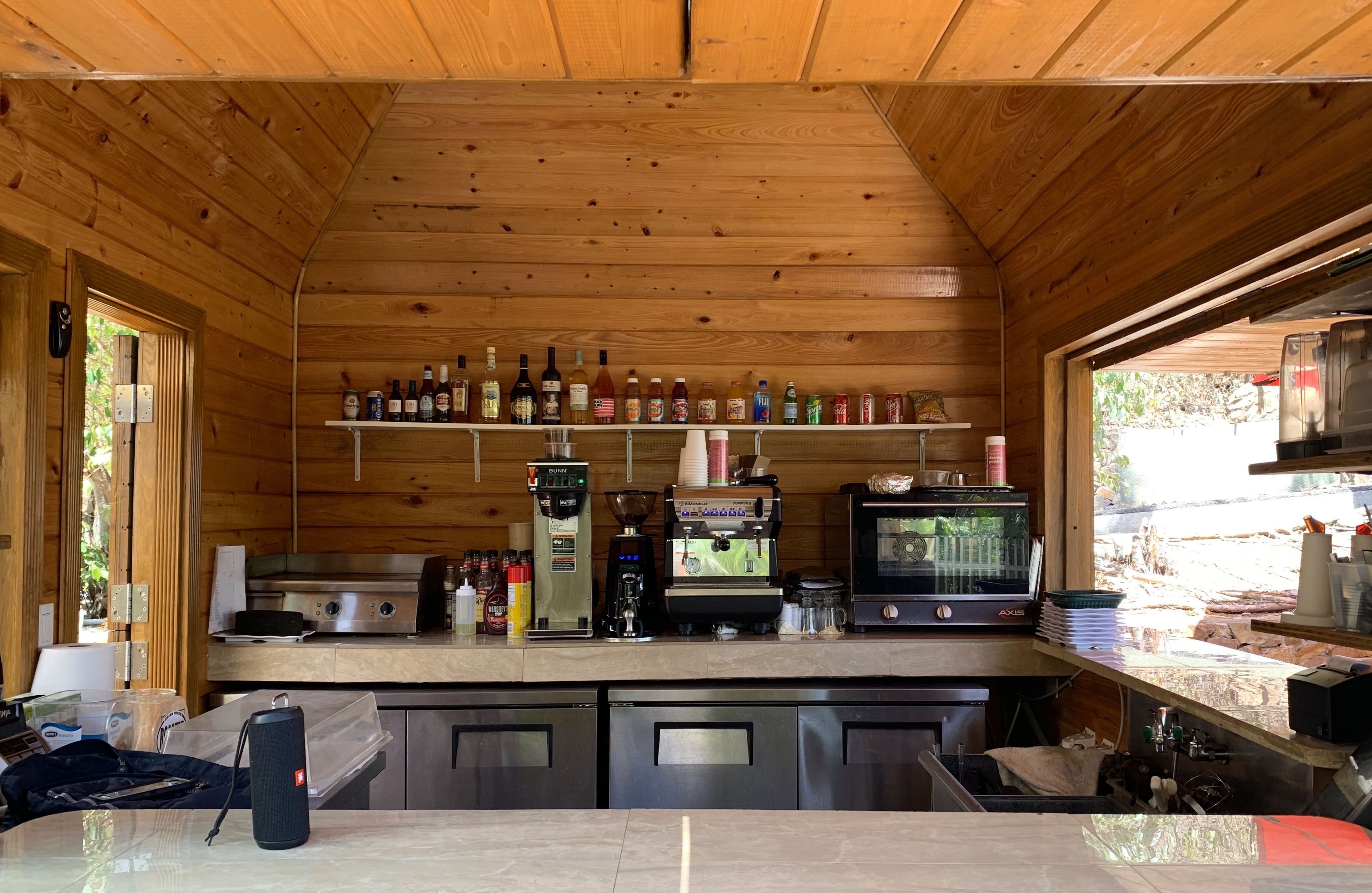 A wooden cabin interior with a kitchen area featuring a coffee machine, a toaster, and a microwave.