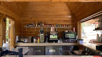A wooden cabin interior with a kitchen area featuring a coffee machine, a toaster, and a microwave.
