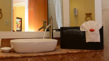 Un baño con un lavabo blanco, una cesta negra y una toalla sobre el mostrador.