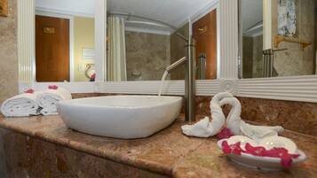 A bathroom with a white sink, marble countertop, and a large mirror.