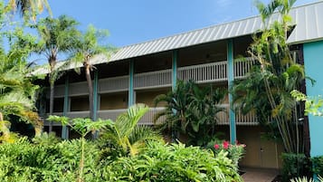 A multi-story hotel with balconies, surrounded by lush tropical vegetation.