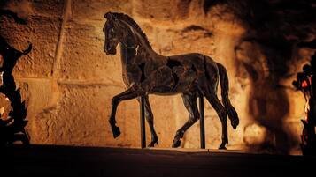 A bronze horse sculpture in a dimly lit room with stone walls.