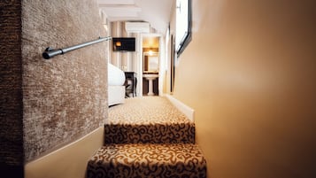 Una escalera alfombrada con un diseño estampado, una barandilla y un televisor montado en la pared.