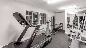 A gym with a treadmill, weight machines, and a mirror.