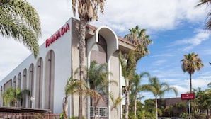 A building with the sign "RAMADA" on the facade, featuring a modern architectural style with arched windows and a flat roof.