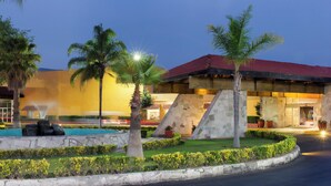 Un hotel con piscina, palmeras y fachada de piedra.