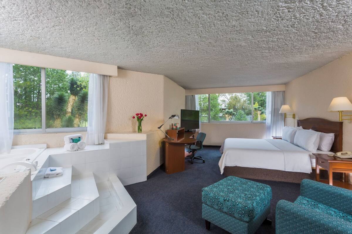 Ein Hotelzimmer mit Bett, Schreibtisch, Stuhl und einer kleinen Sitzecke.