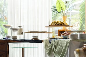 A buffet setup with various dishes and a decorative plant.