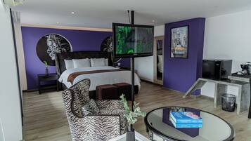 Ein Hotelzimmer mit einem Bett, einem zebra-gemusterten Sessel, einem Fernseher, einer Kaffeemaschine und einem kleinen Tisch mit Büchern.